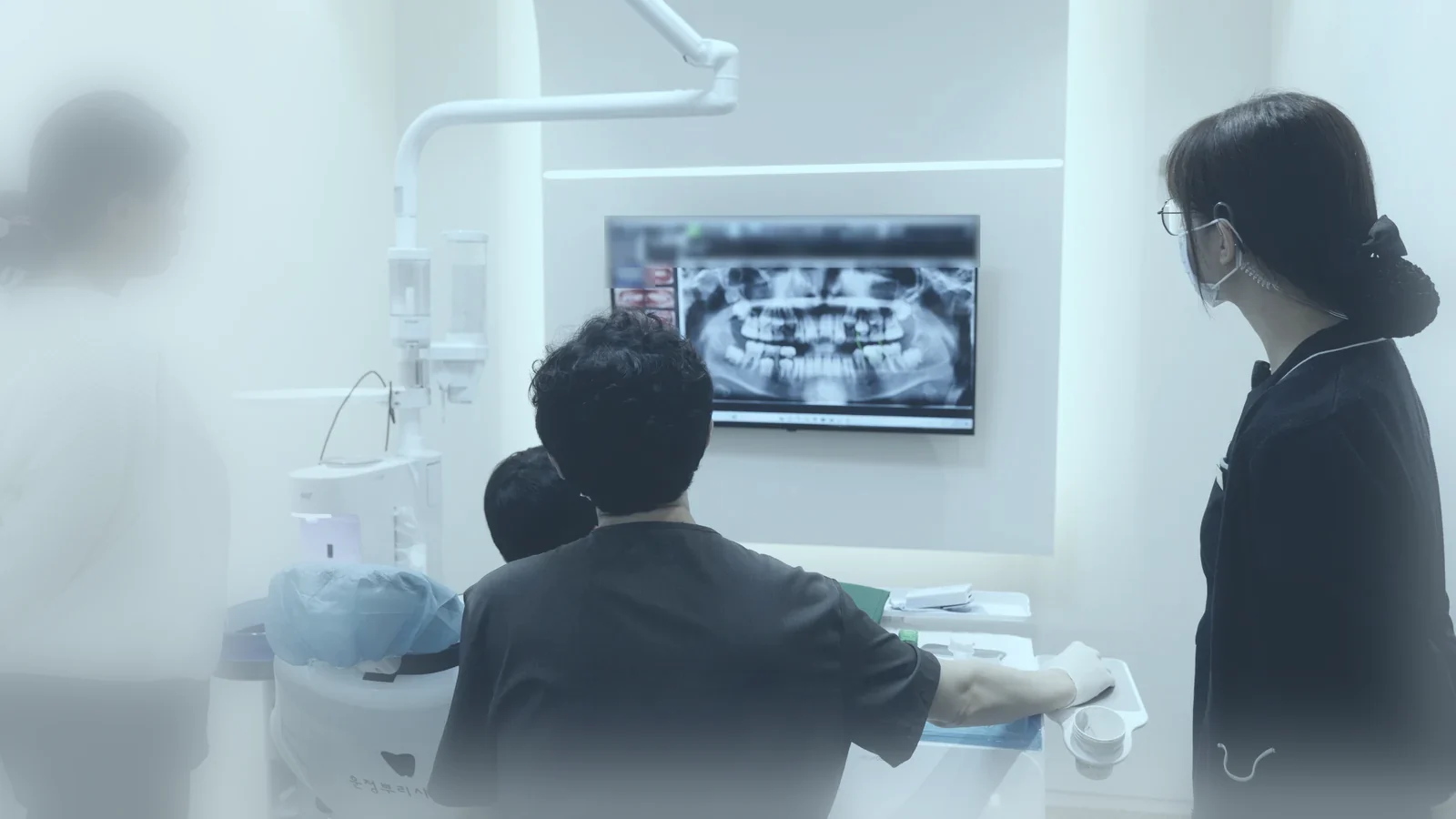 보호자와 아이가 원장, 스태프와 함께 모니터의 파노라마 엑스레이를 보는 모습